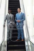 African-american young male executive talking with mature male executive in escalator
