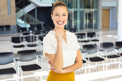 Young Caucasian female executive looking at camera while standing in empty conference room