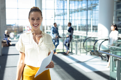 Caucasian female executive looking at camera while walking in modern office