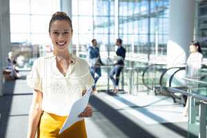 Caucasian female executive looking at camera while walking in modern office