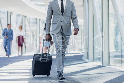 African american businessman walking in corridor with suitcase in modern office