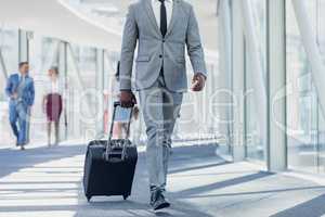 African american businessman walking in corridor with suitcase in modern office