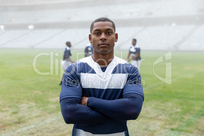 Male rugby player standing with arms crossed in stadium