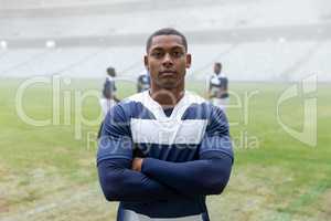 Male rugby player standing with arms crossed in stadium