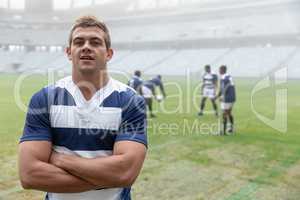Caucasian Male rugby player standing with arms crossed in stadium