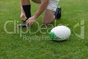 Caucasian male rugby player tying shoelaces in the stadium