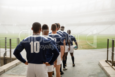 Diverse male rugby players standing at the entrance of stadium in a row for match