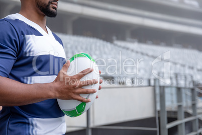 African American male rugby ball player holding a rugby ball in stadium