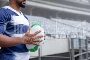 African American male rugby ball player holding a rugby ball in stadium