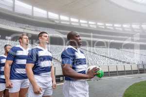 Diverse male rugby player standing in a row at the entrance of stadium