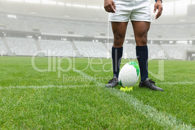 African American male rugby player standing near rugby ball in stadium