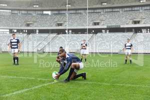 African American Male rugby player placing rugby ball on a stand in stadium