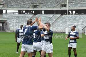 Diverse male rugby players celebrating goal in stadium