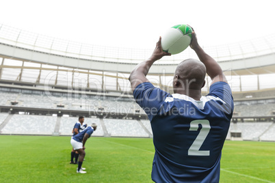 African American male rugby player throwing rugby ball in stadium