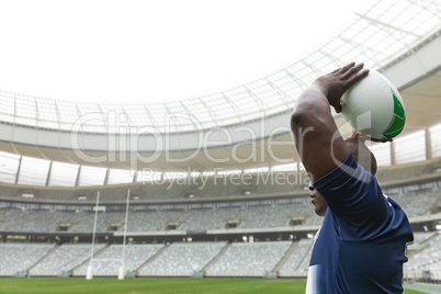 African American male rugby player throwing rugby ball in stadium