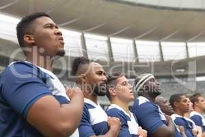 Group of diverse male rugby players taking pledge together in stadium