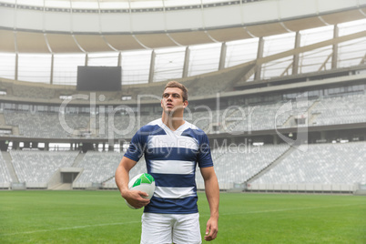 Caucasian rugby player standing with rugby ball in stadium