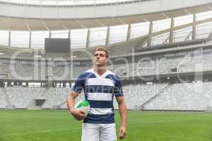 Caucasian rugby player standing with rugby ball in stadium