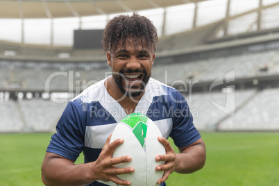 Happy African American Rugby player standing with rugby ball in stadium