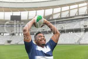 Happy African American Rugby player throwing rugby ball in the stadium