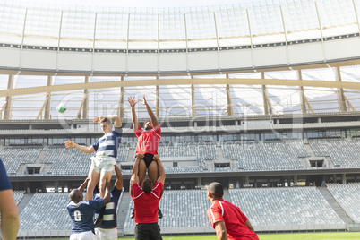 Male rugby players playing rugby match in stadium