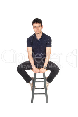 Handsome tall young man sitting on chair in the studio