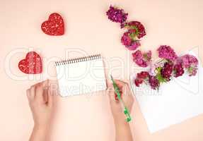 two female hands and an open spiral notebook with white blank sh