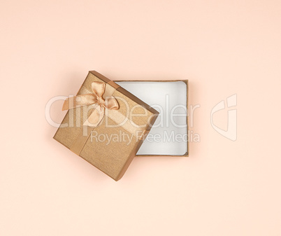 open golden gift box with a bow on a beige background