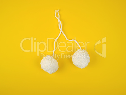 two white fluffy pom-poms of white cotton thread