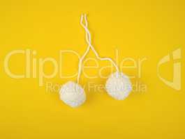 two white fluffy pom-poms of white cotton thread