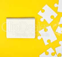 open notebook on a yellow background, next to large blank puzzle