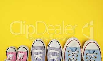 lot of textile worn sneakers of different sizes on a yellow back