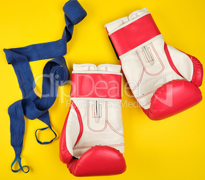 pair of red leather boxing gloves and blue textile bandage,
