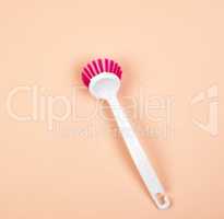 kitchen brush with white plastic handle on a beige background