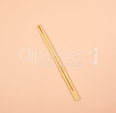 two wooden chopsticks on a beige background