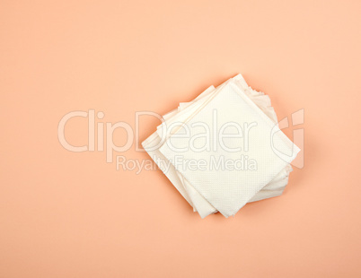 stack of white paper napkins on a beige background, top view