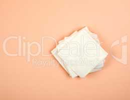 stack of white paper napkins on a beige background, top view