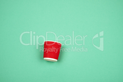 red paper cup with corrugated edges for hot drinks on a green ba