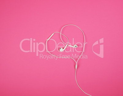 white headphones with a cable on a pink background