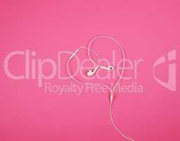 white headphones with a cable on a pink background