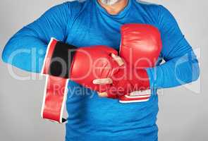 athlete in blue clothes, hands are rewound with red textile band