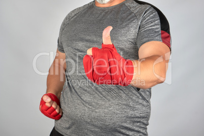 sportsman's hands wrapped in red elastic sports bandage show a l