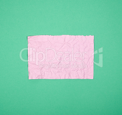 empty crumpled pink rectangular sheet of paper on a green backgr