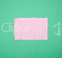 empty crumpled pink rectangular sheet of paper on a green backgr