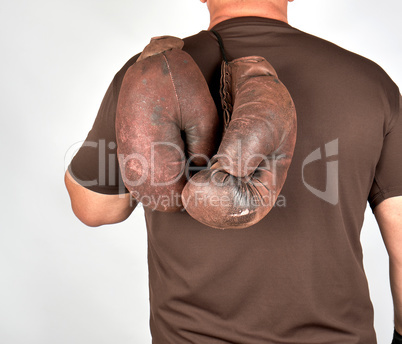 male athlete holds a pair of very old vintage boxing gloves