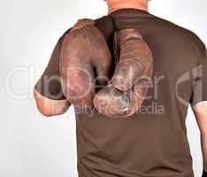 male athlete holds a pair of very old vintage boxing gloves