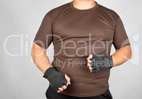 adult athlete in brown clothes with bandaged hands black textile