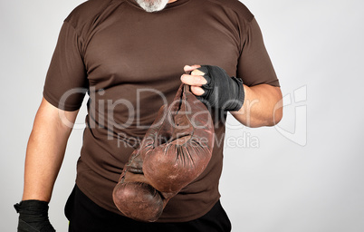 athlete in brown clothes holds very old vintage leather boxing g
