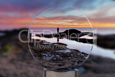 Lone man through a crystal ball on the rocks at sunset at Treasu