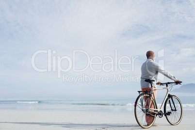 Man holding a bicycle on the beach